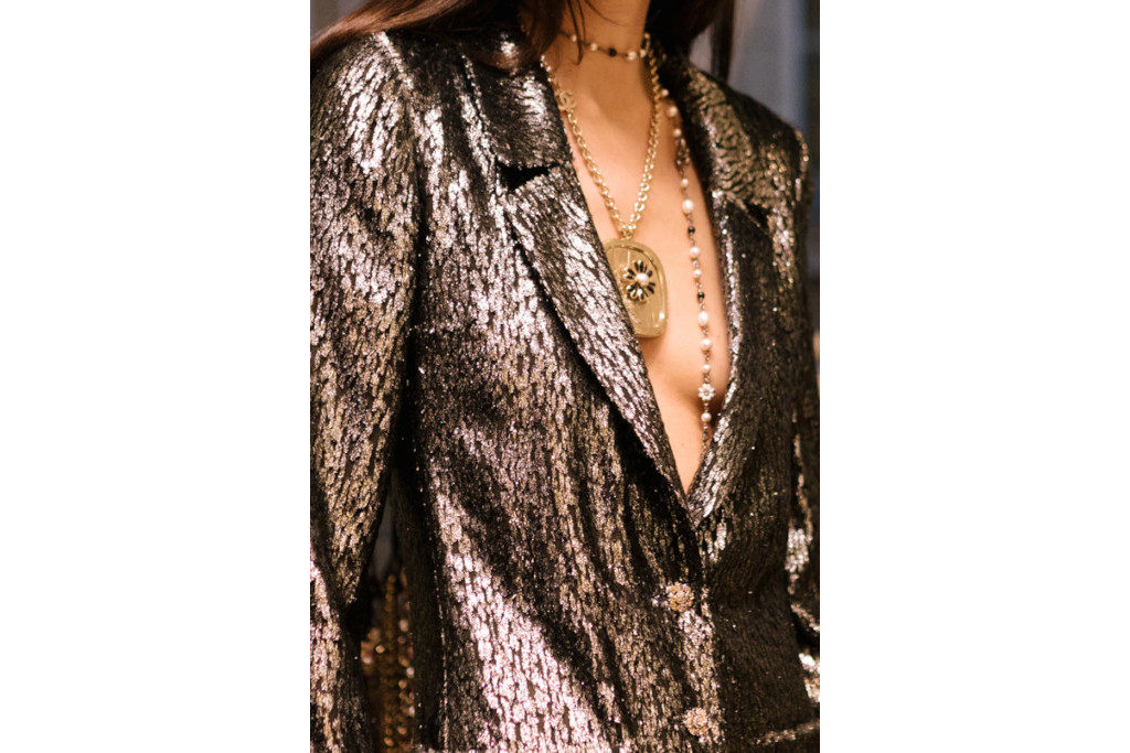 Close up of woman wearin metallic blazer and stacked necklaces