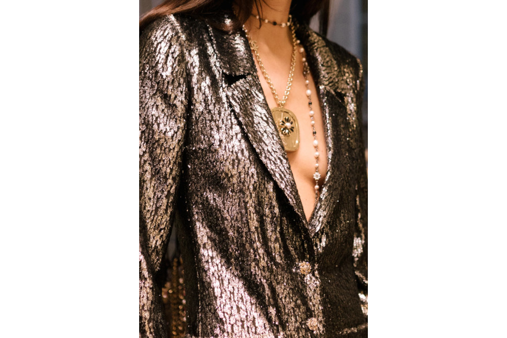 Close up of woman wearin metallic blazer and stacked necklaces