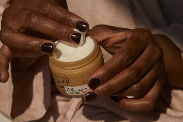 Hands holding a pot of skin cream