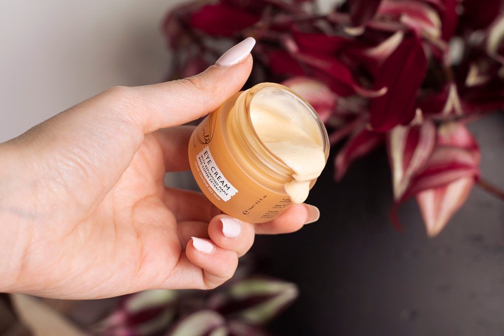 Hand holding a tub of skin cream