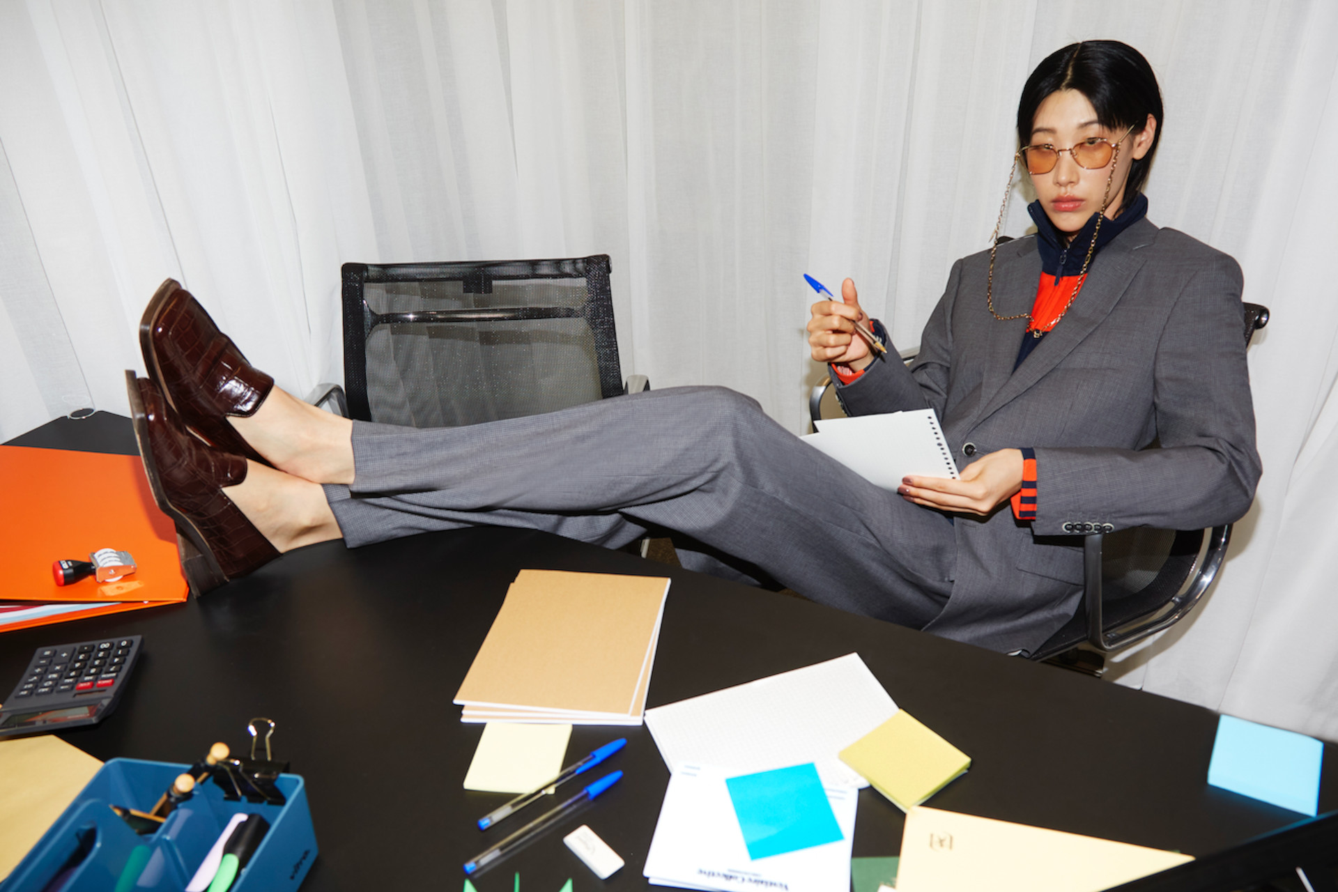 Model in grey suit and loafers with legs up on the table