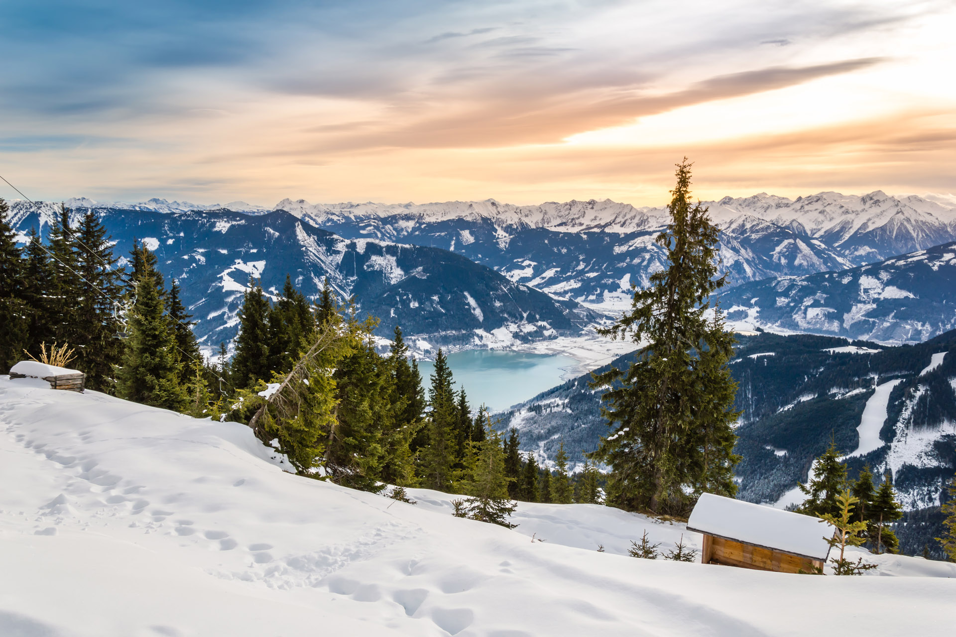 Zell am See and Schmitten town at Zeller lake in winter. View from Schmittenhohe mountain, snowy ski resort slope in the Alps mountains, Austria. Stunning landscape, snow and sunset sky near Kaprun