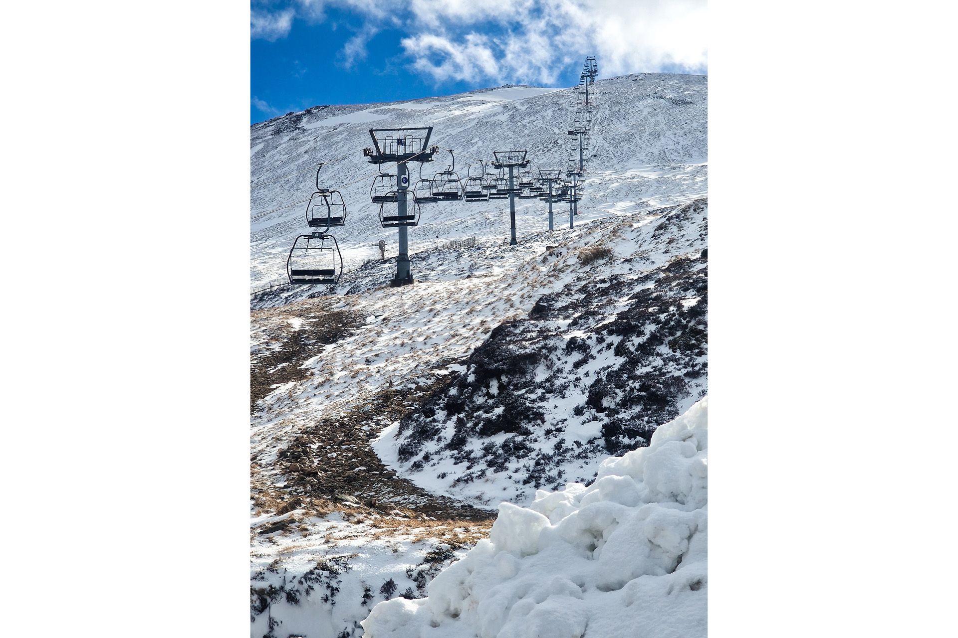 Ski chairlift ar Glenshee on a sunny snowy day. The chairlift stops just below the summit of The Cairnwell a Scottish munro.
