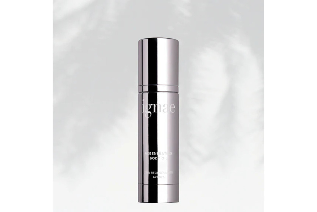 Silver tube of body oil in front of grey background