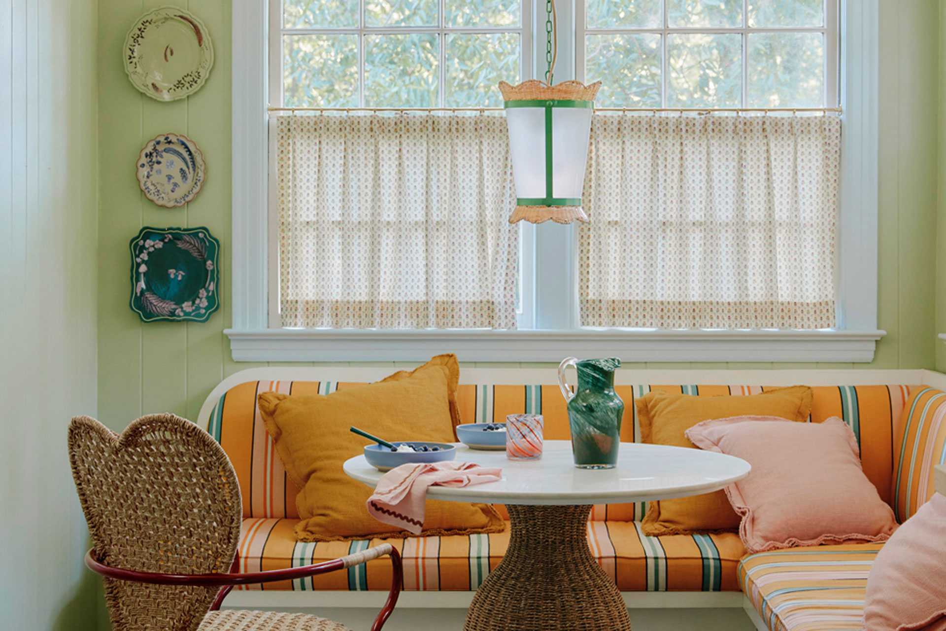 The Matilda Goad and Anthropologie collection, with a kitchen, featuring a heart shaped chair, yellow sofa seating, and a cafe curtain in the backgroundq