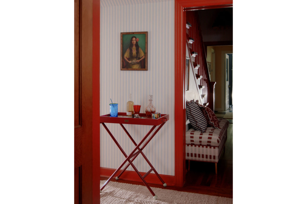 The Matilda Goad x Anthropologie collaboration with a red bar trolley in a house with a painting above it