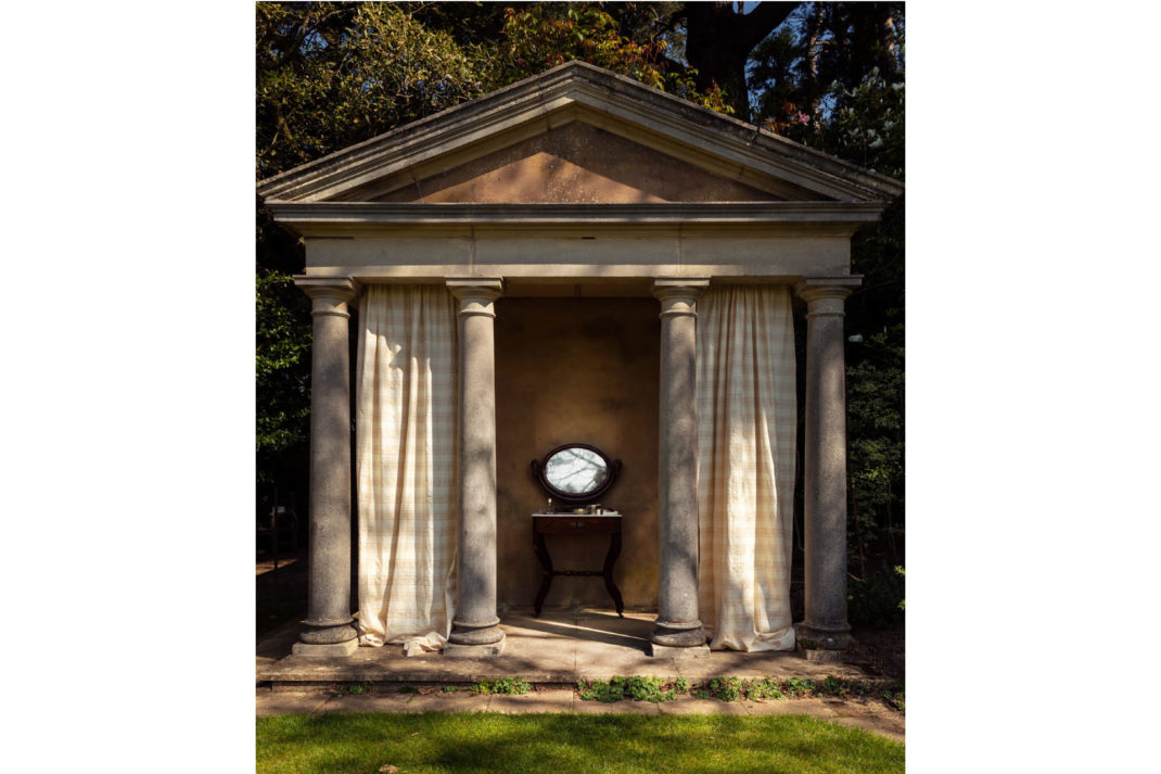 an ancient greek temple that's had a modern update with gingham print curtains in between the columns, that's done by Soane 