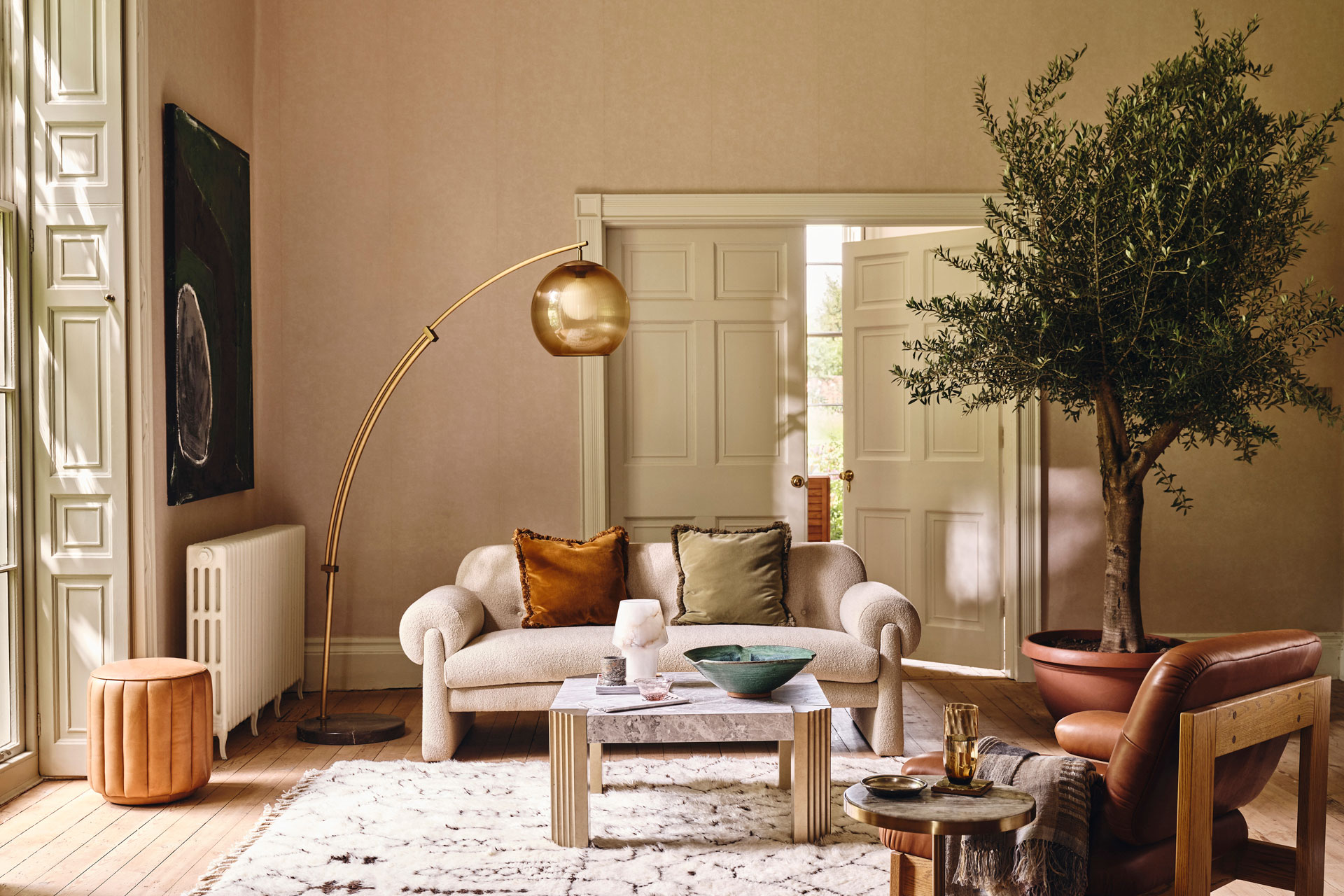 a living room with soft furnishings by Soho Home, featuring a large indoor trees, plush sofas and arm chairs and a textured rug