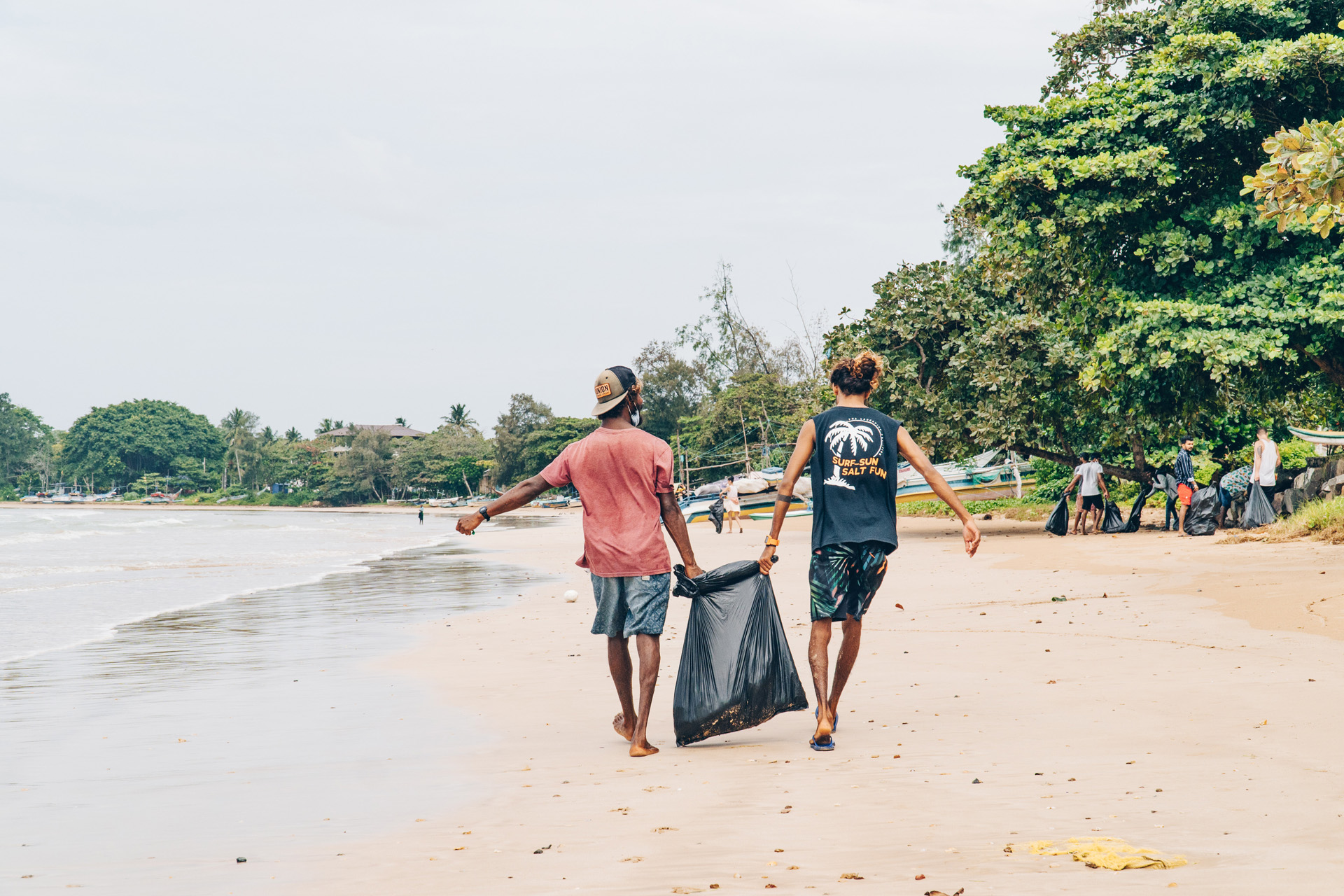 two people cleaning up a beach