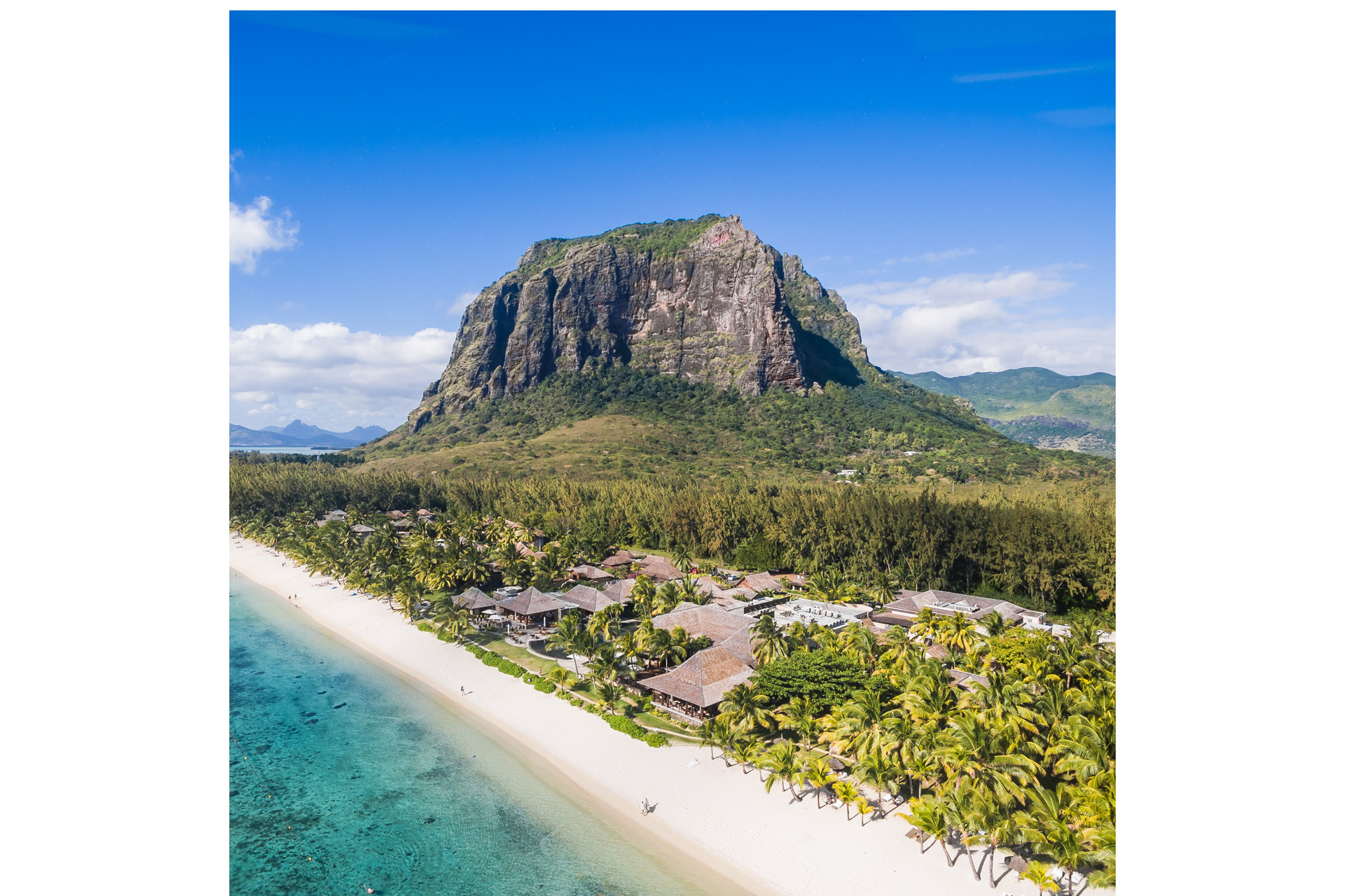 LUX* Le Morne from a distance, with blue ocean in the foreground and a mountain in the background