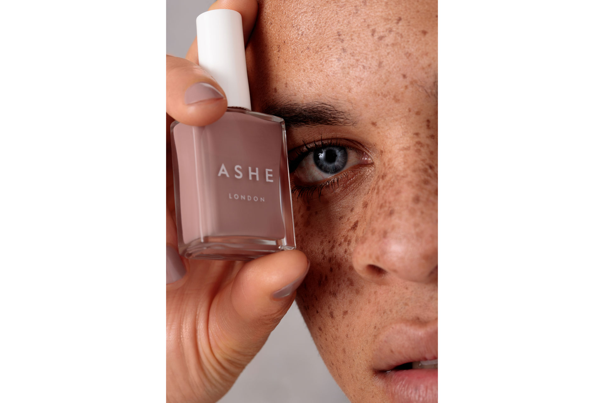 Close up of woman's face with a bottle of nail polish
