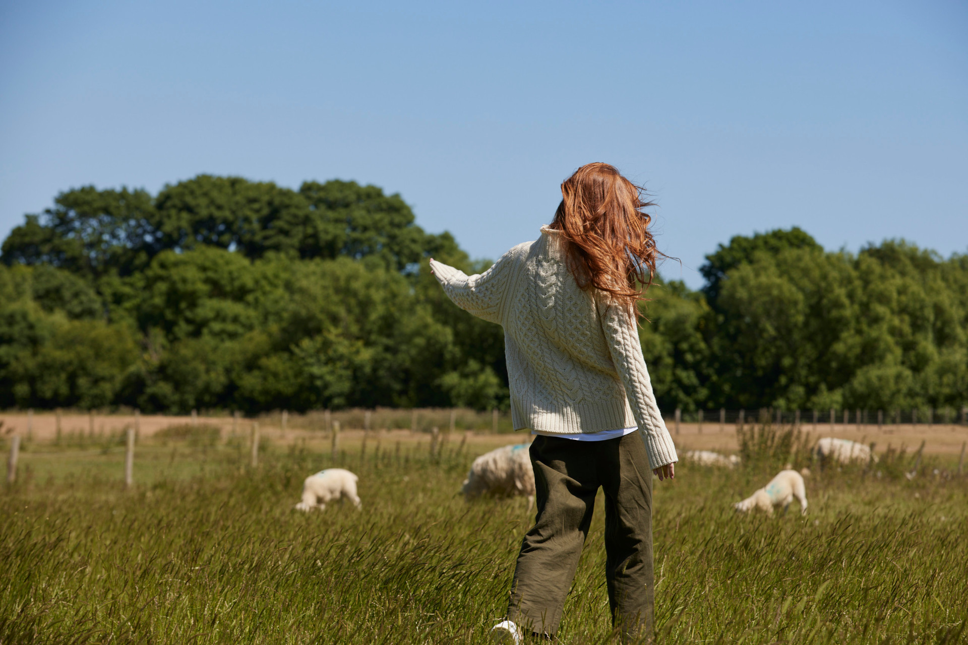 Woman walking through field in wool jumper