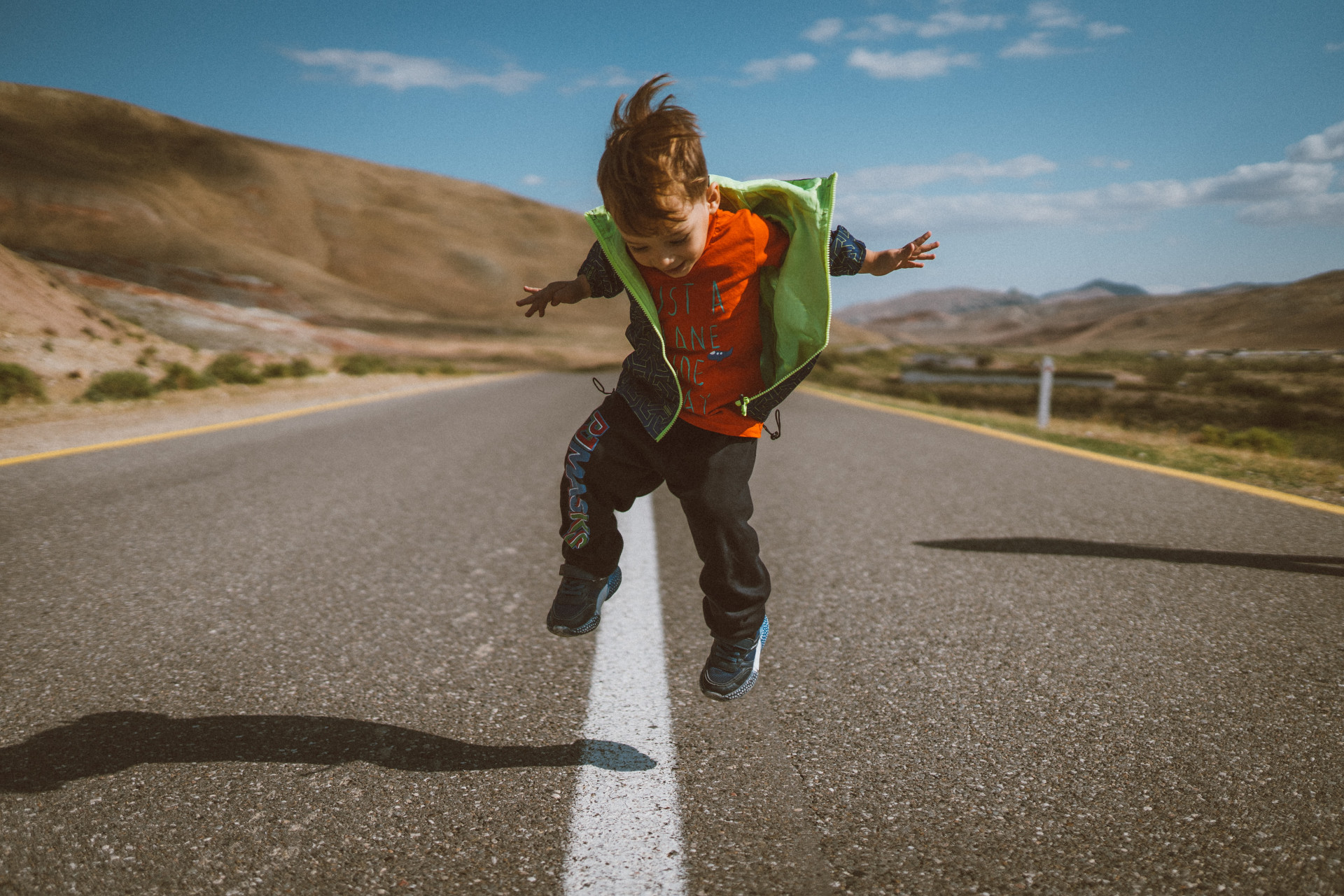 boy jumping in the middle of an empty road