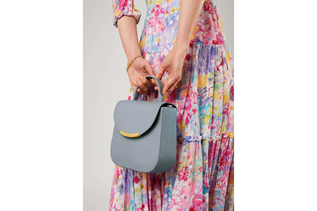 Close up of someone in long floral dress holding blue bag