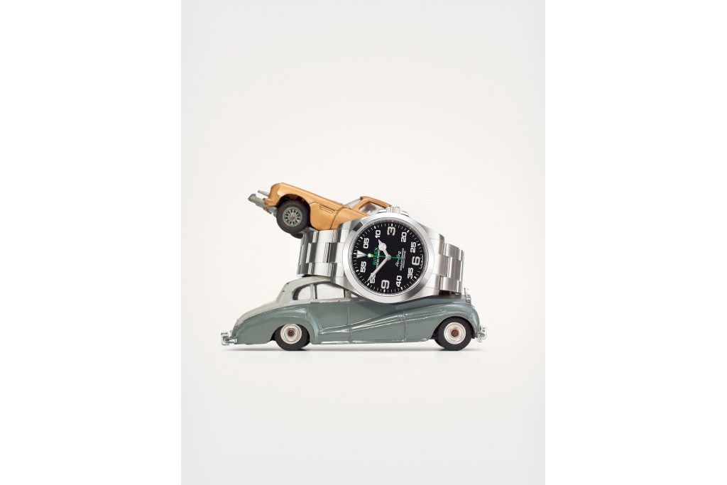 Silver watch perched between two toy cars