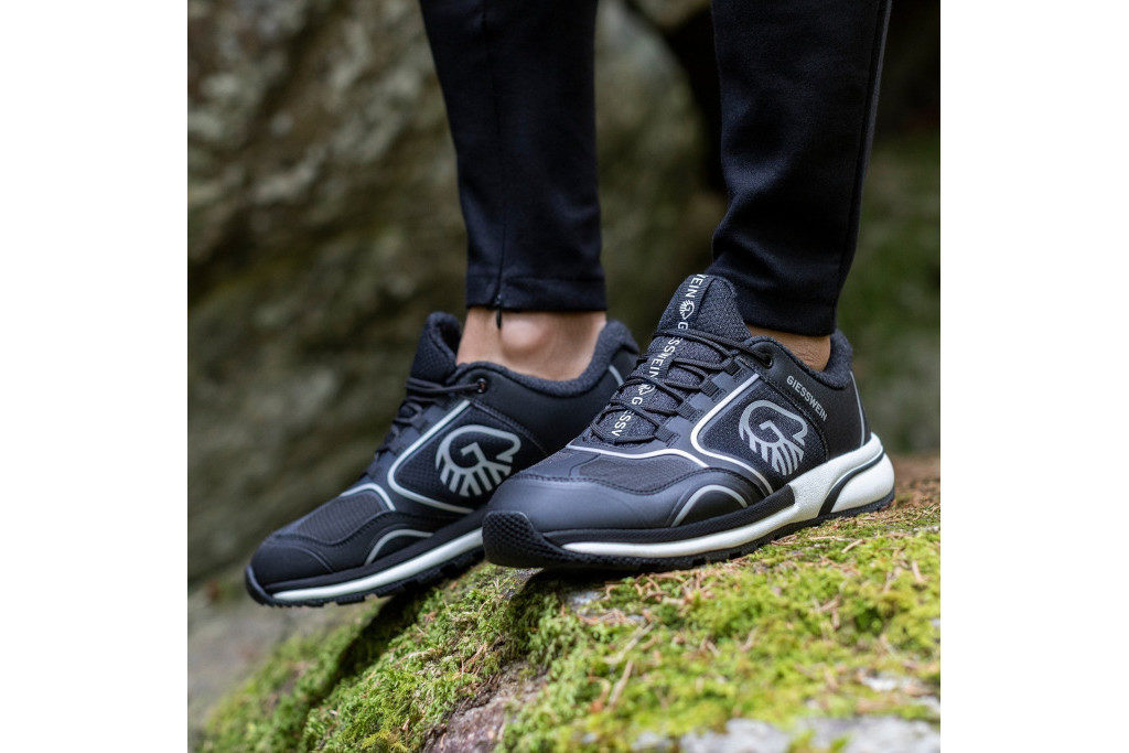 Close up of someone's feet in trainers, stood on a mossy rock