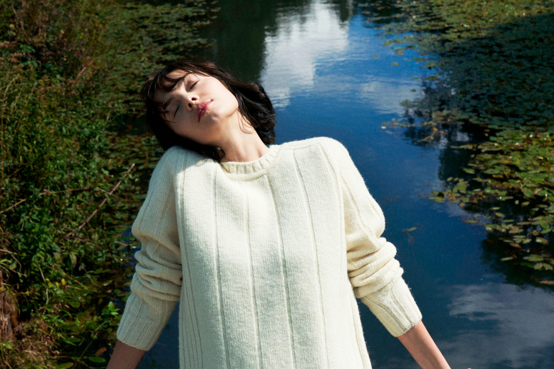 Woman leaning backwards outdoors wearing cream jumper