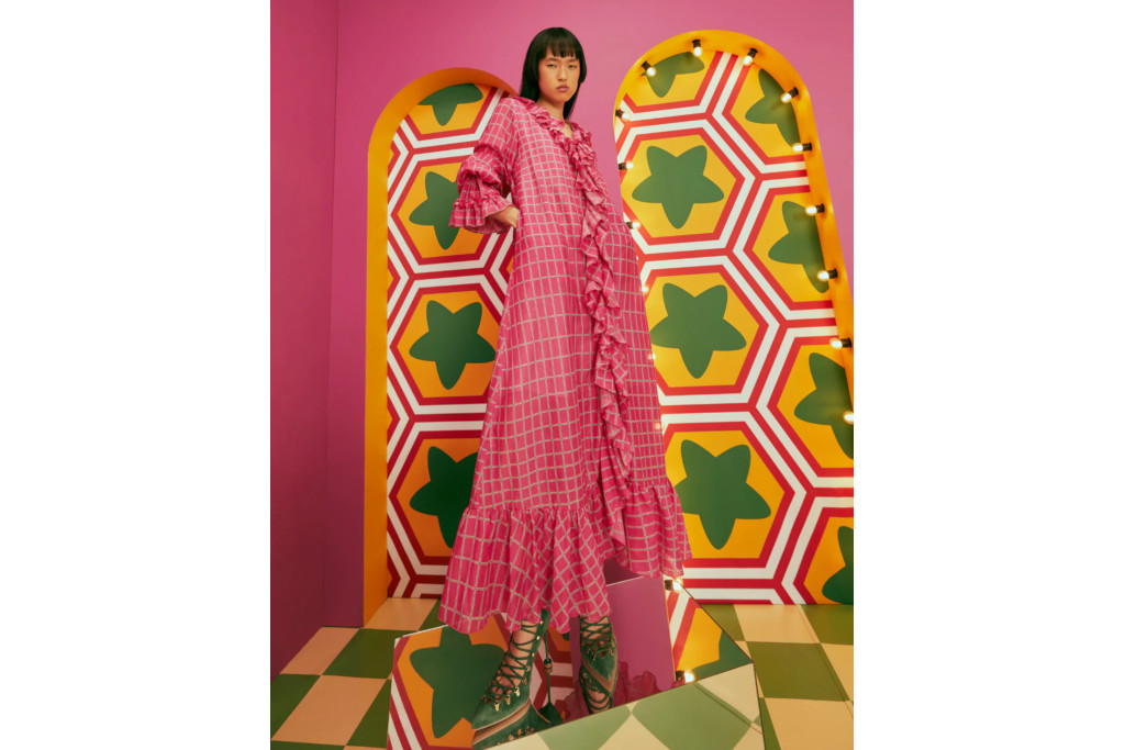 Model in pink check frill dress stood in front of pink, yellow and green patterned background