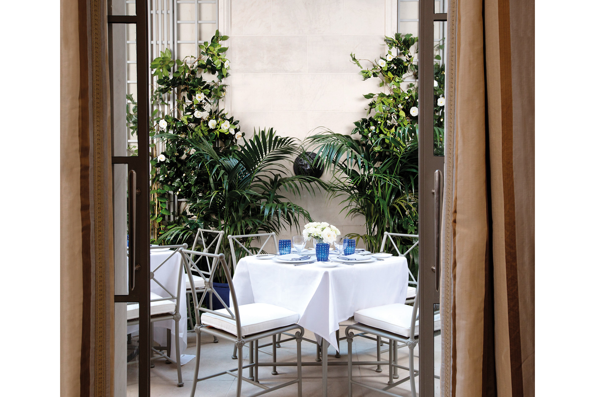 a white set table outside, surrounded by plants