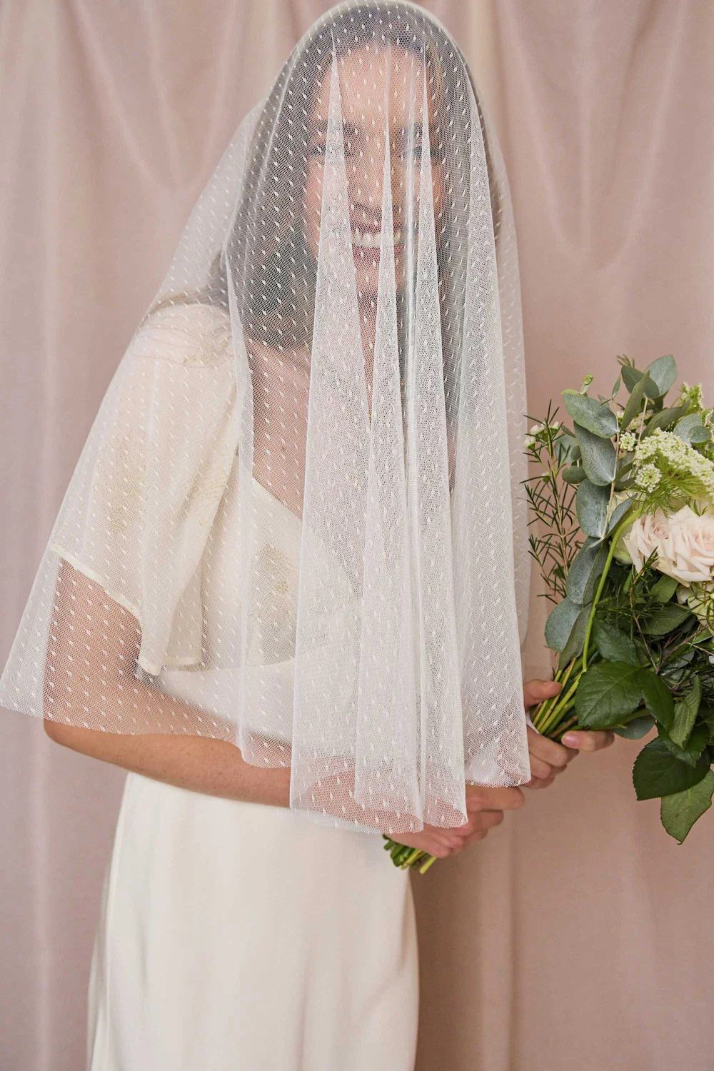 Woman wearing veil and holding bouquet | wedding accessories brands