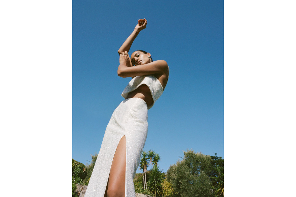 Model in white separates stood in front of blue sky