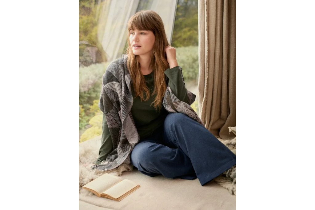 Woman sat on floor weaing cardigan and flowy trousers