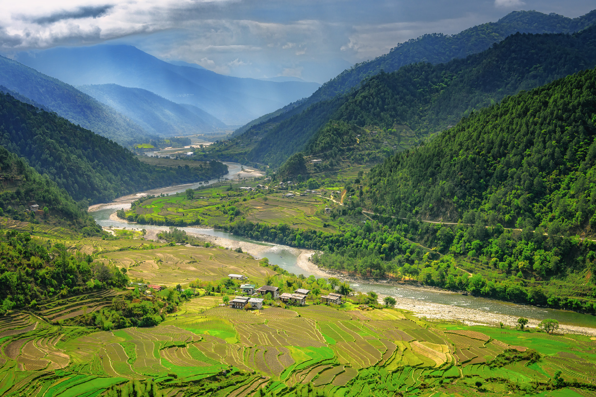 Valley in Bhutan near Punakha with rice fields and typical houses. Travel to Bhutan and enjoy the beautiful landscape of farms and mountains in this buddhist country.