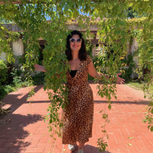 Alanna Ospina in sunglasses peering through some hanging leaves