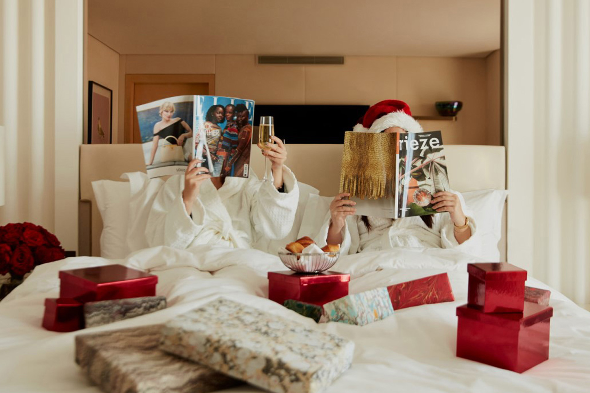 two people in bed with christmas gifts and magazines