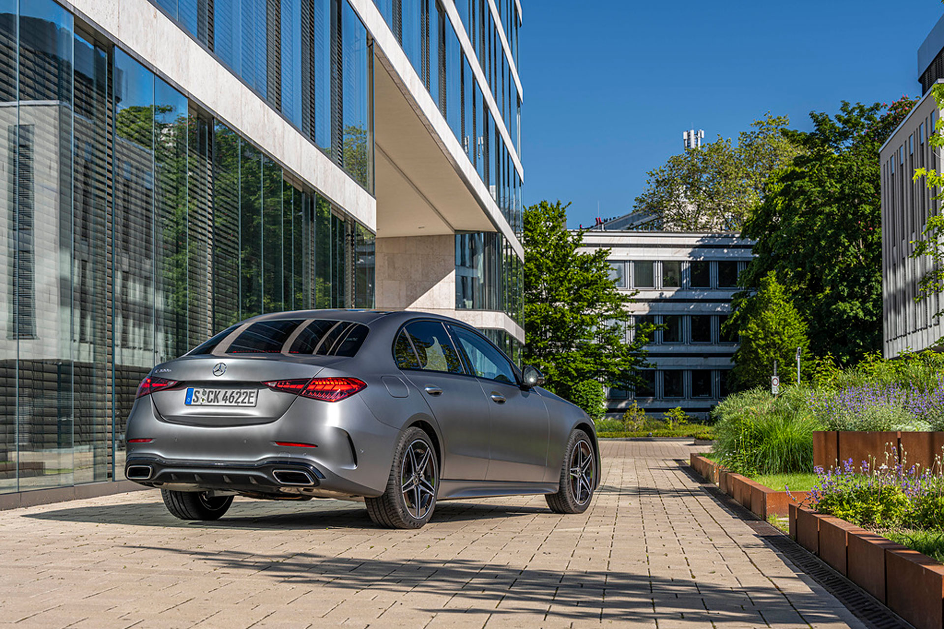 a rear view of the Mercedes 300 e, in a verdant office building backdrop