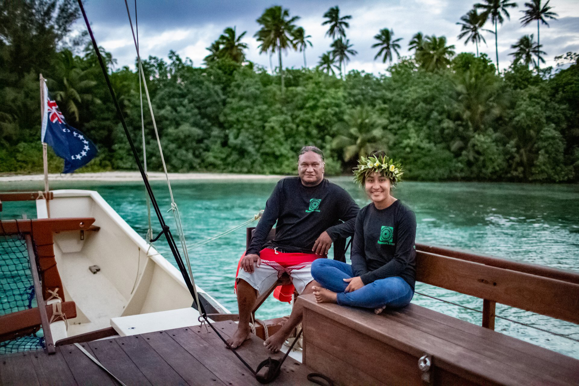 a man and a woman sat on a boat with turquoise water