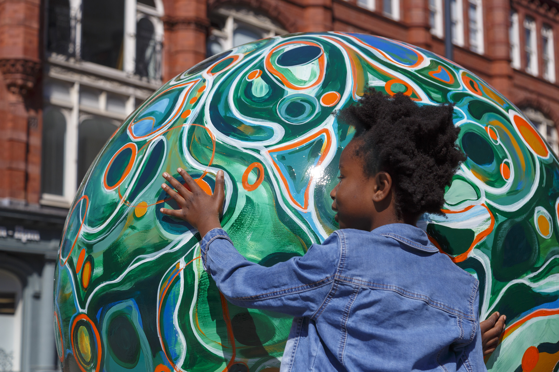 a young boy touching a globe sculpture