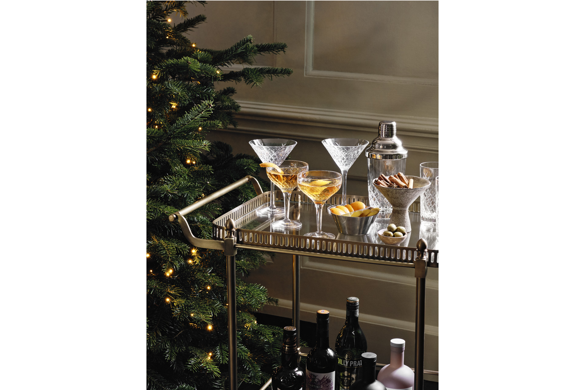 a bar cart with cocktails and a christmas tree in the background