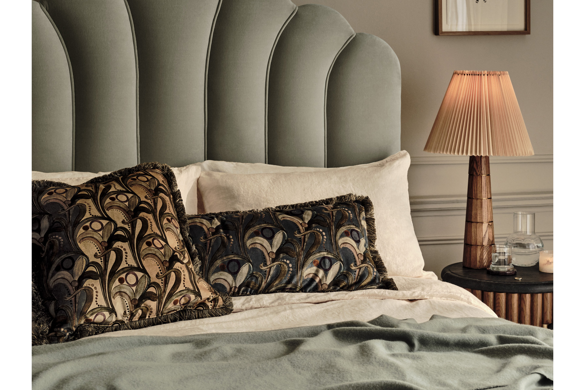 a bed with multicoloured cushions and a side lamp