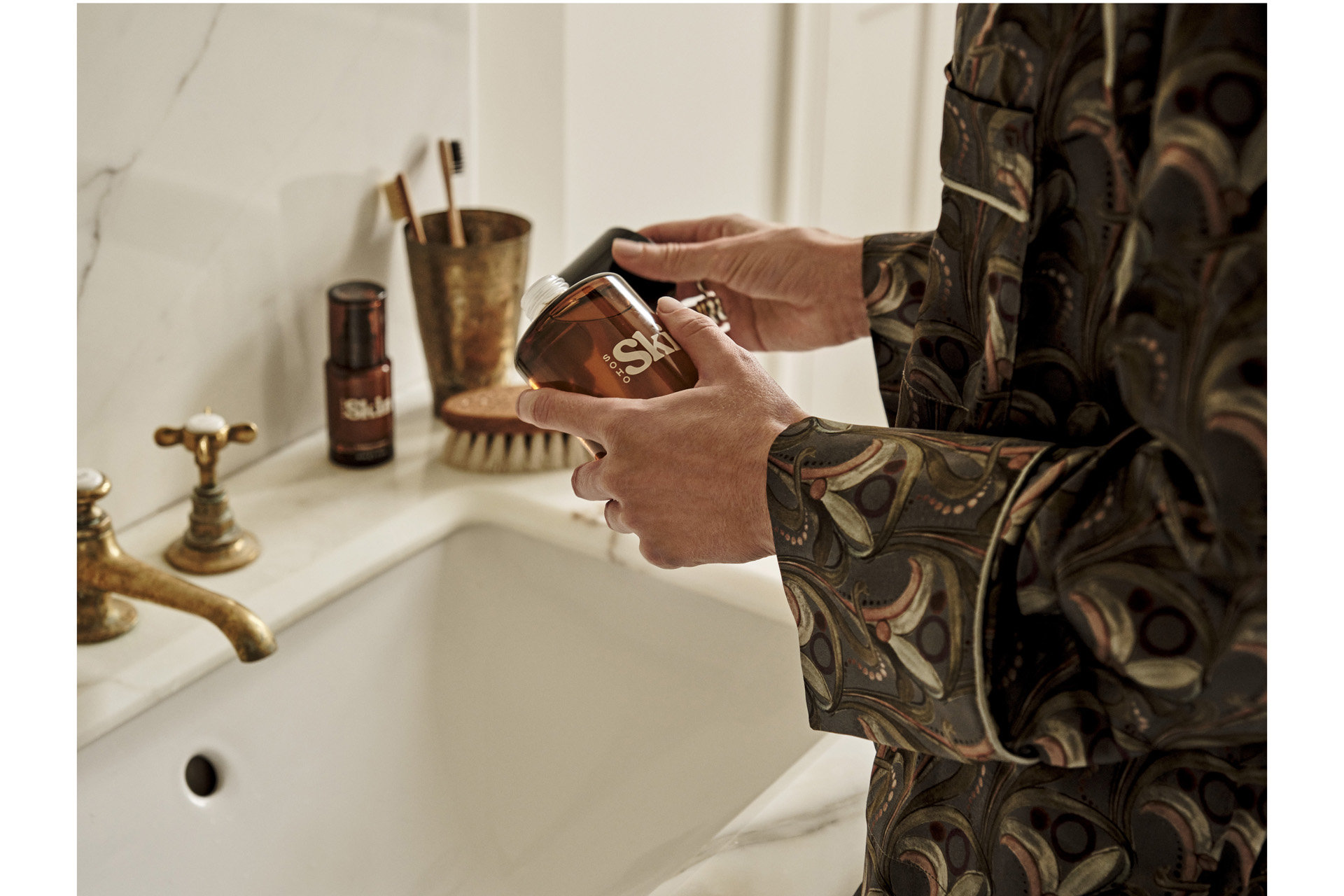 someone holding a skincare product over a white vanity sink