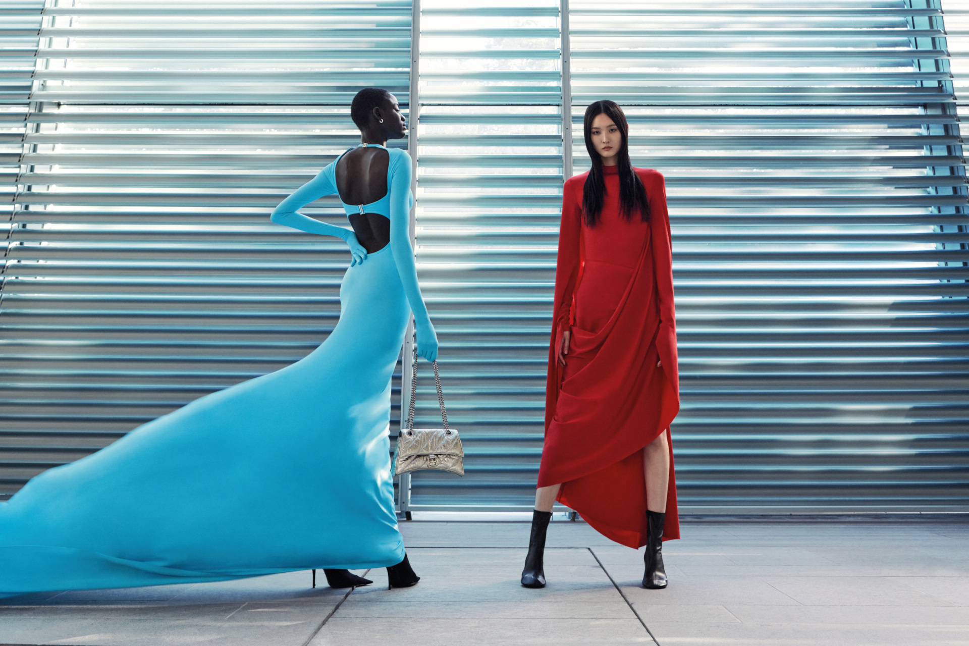 Two women stood together in blue and red dresses