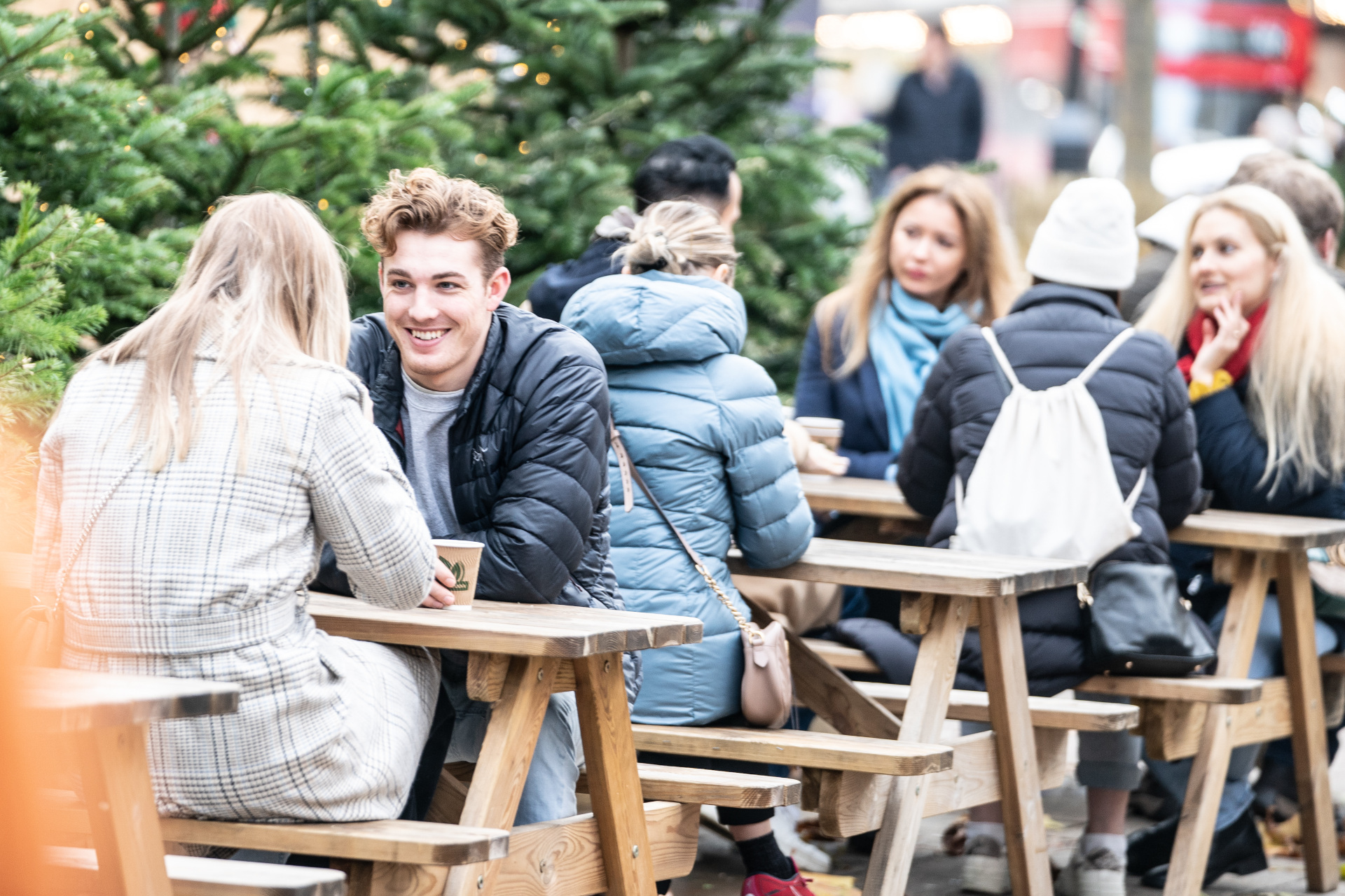 People sat at benches outdoors during winter