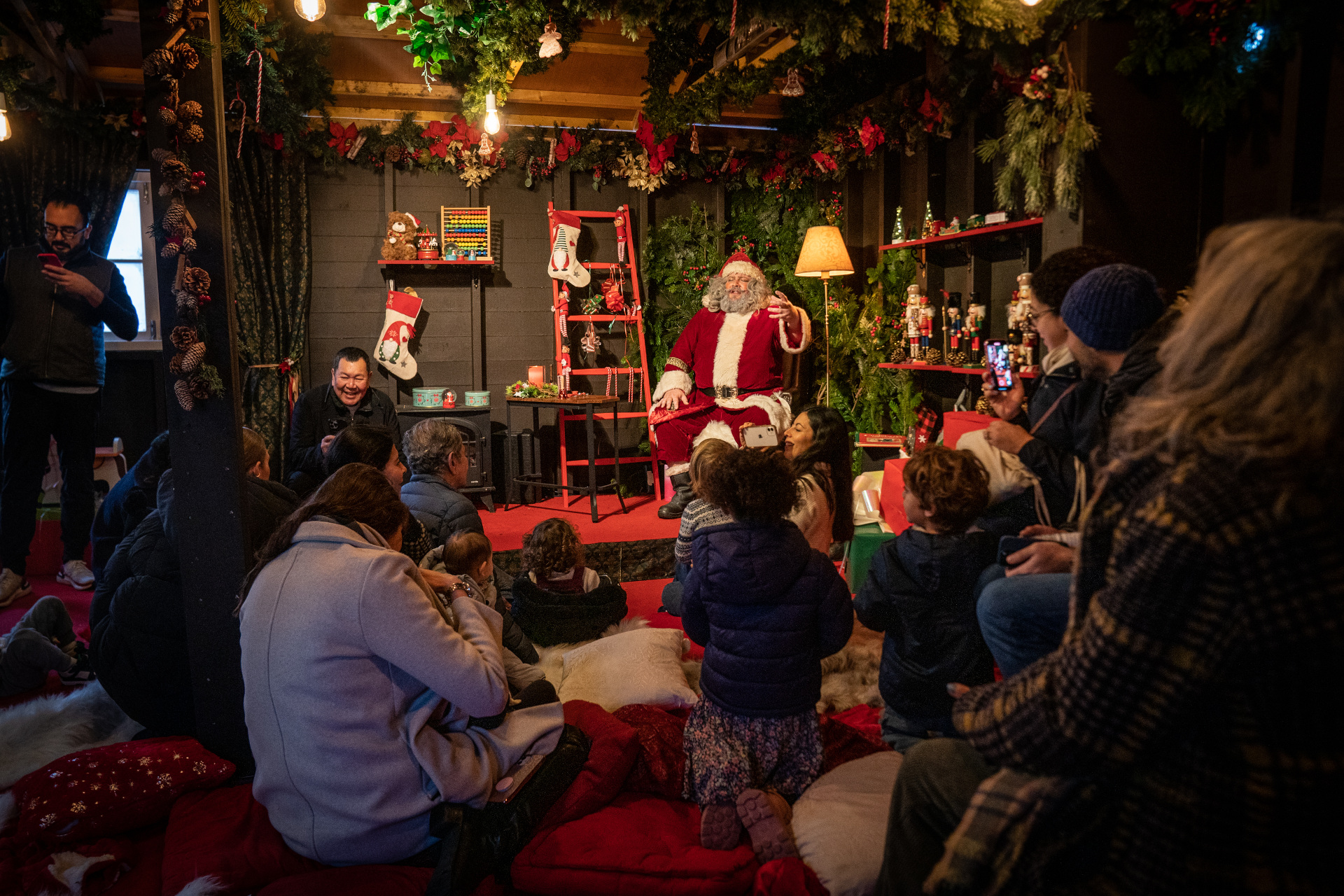 Santa Claus sat with circle of children and parents around him