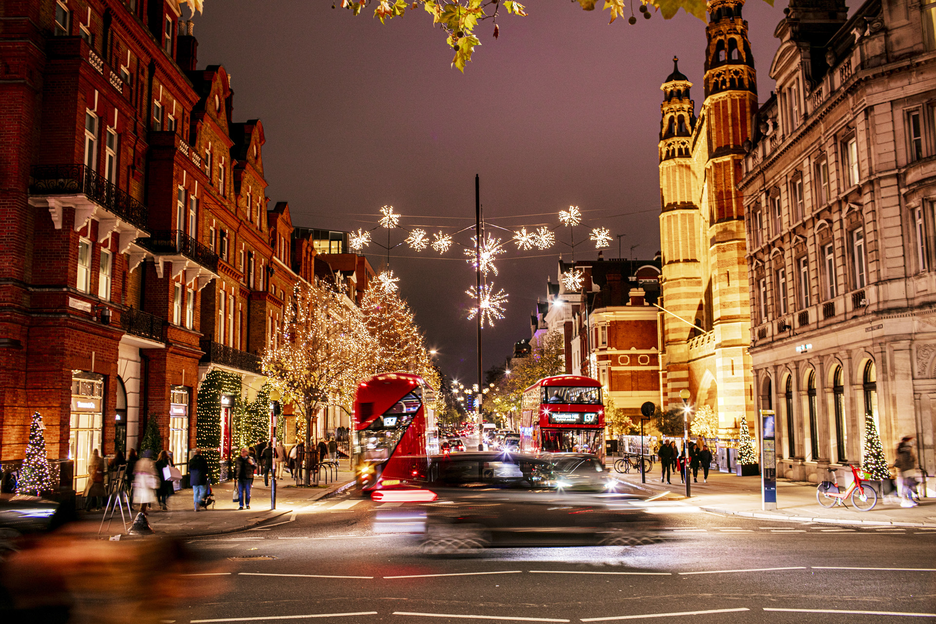 christmas lights over a pretty London street with red buses