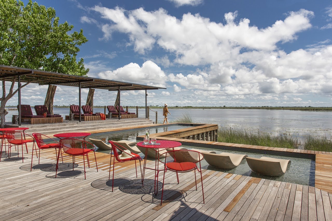 a swimming pool and lake with sun loungers