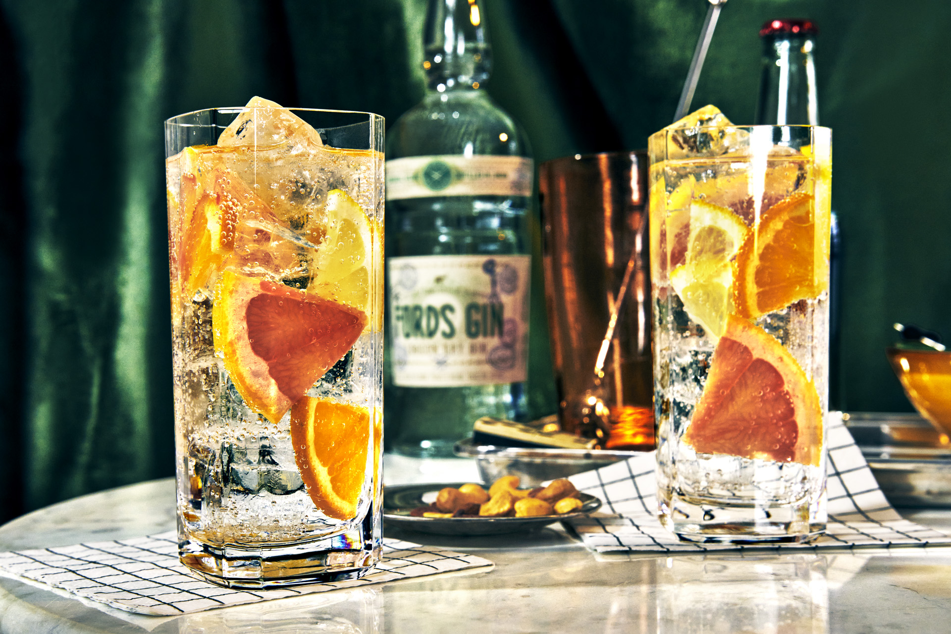 glasses of G&T with orange slices and a bottle of gin