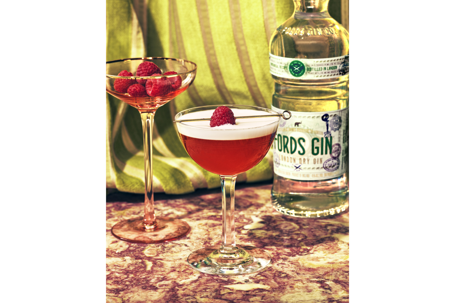 a French 75 cocktail with a bottle of Fords Gin behind