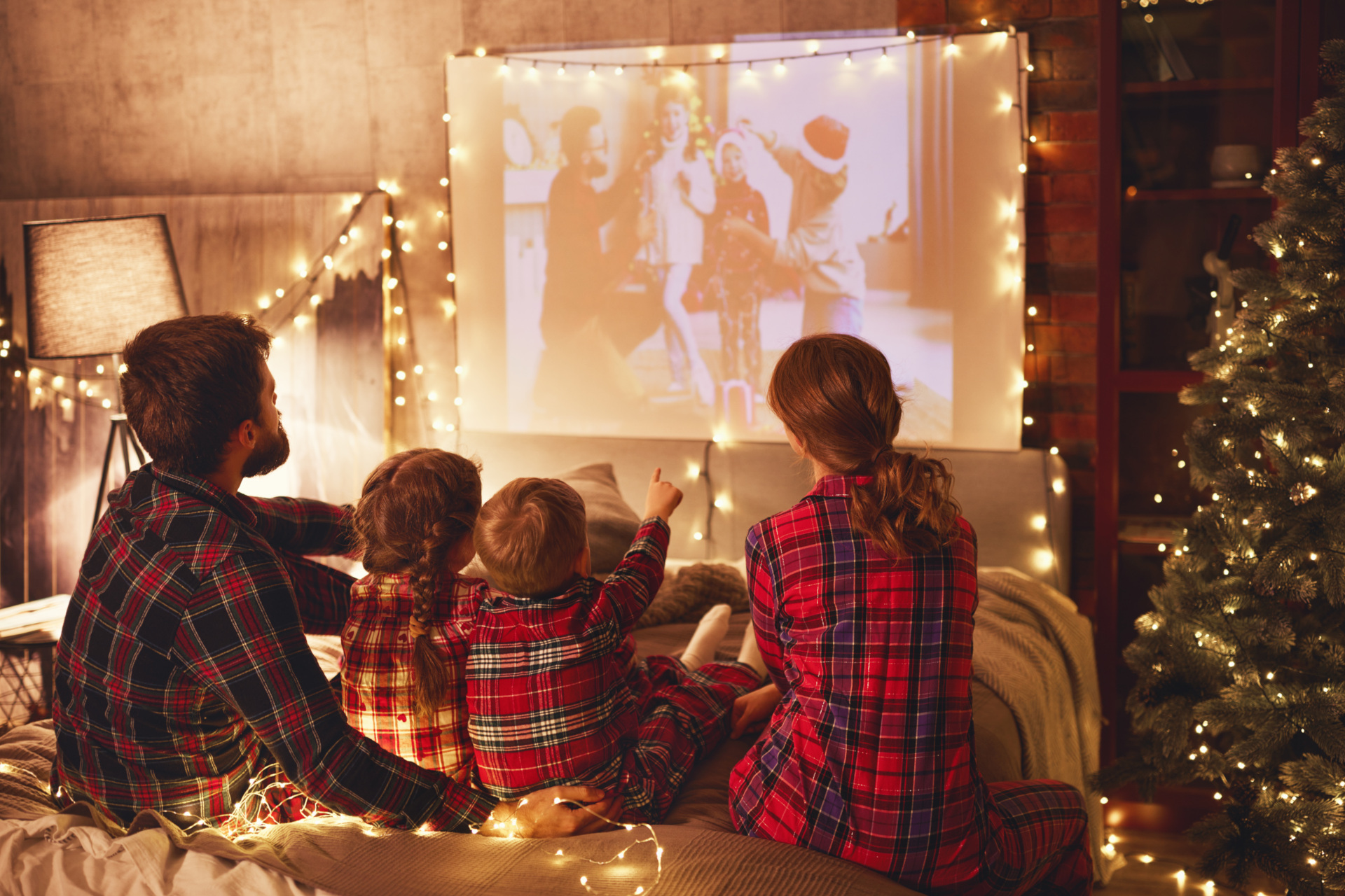 Family watching Christmas film in matching pyjamas