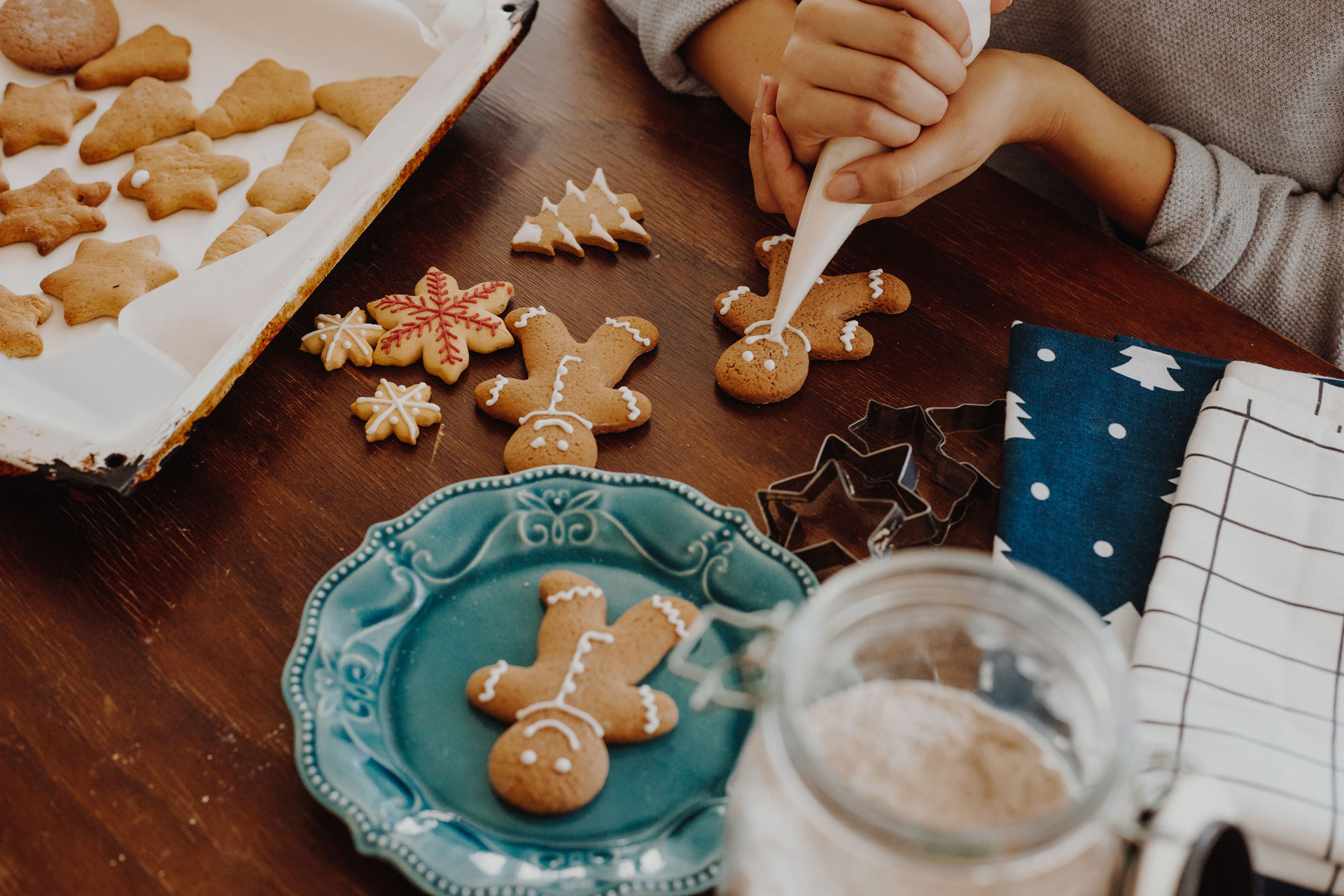 Women decorating gingerbread biscuits, Christmas is near and she prepare for holidays.