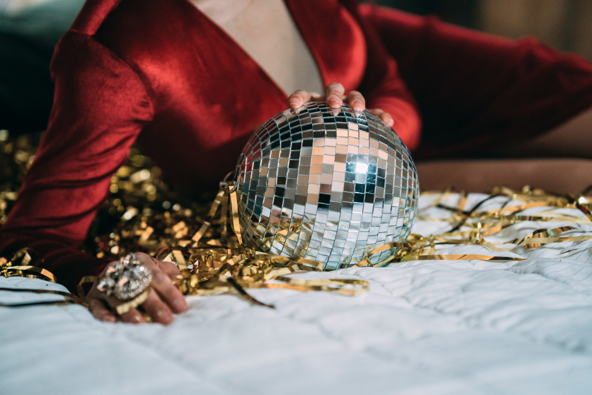 Woman in red velvet dress laying with disco ball