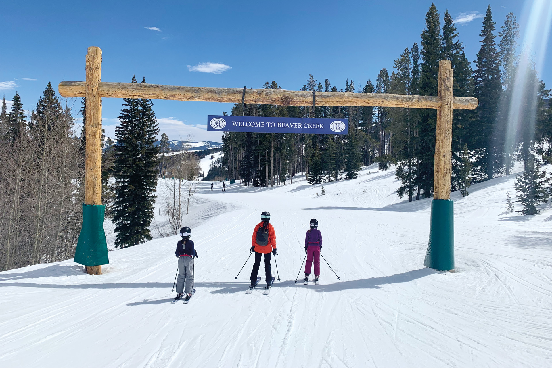 three people skiing under a sign that reads 'welcome to beavercreek'