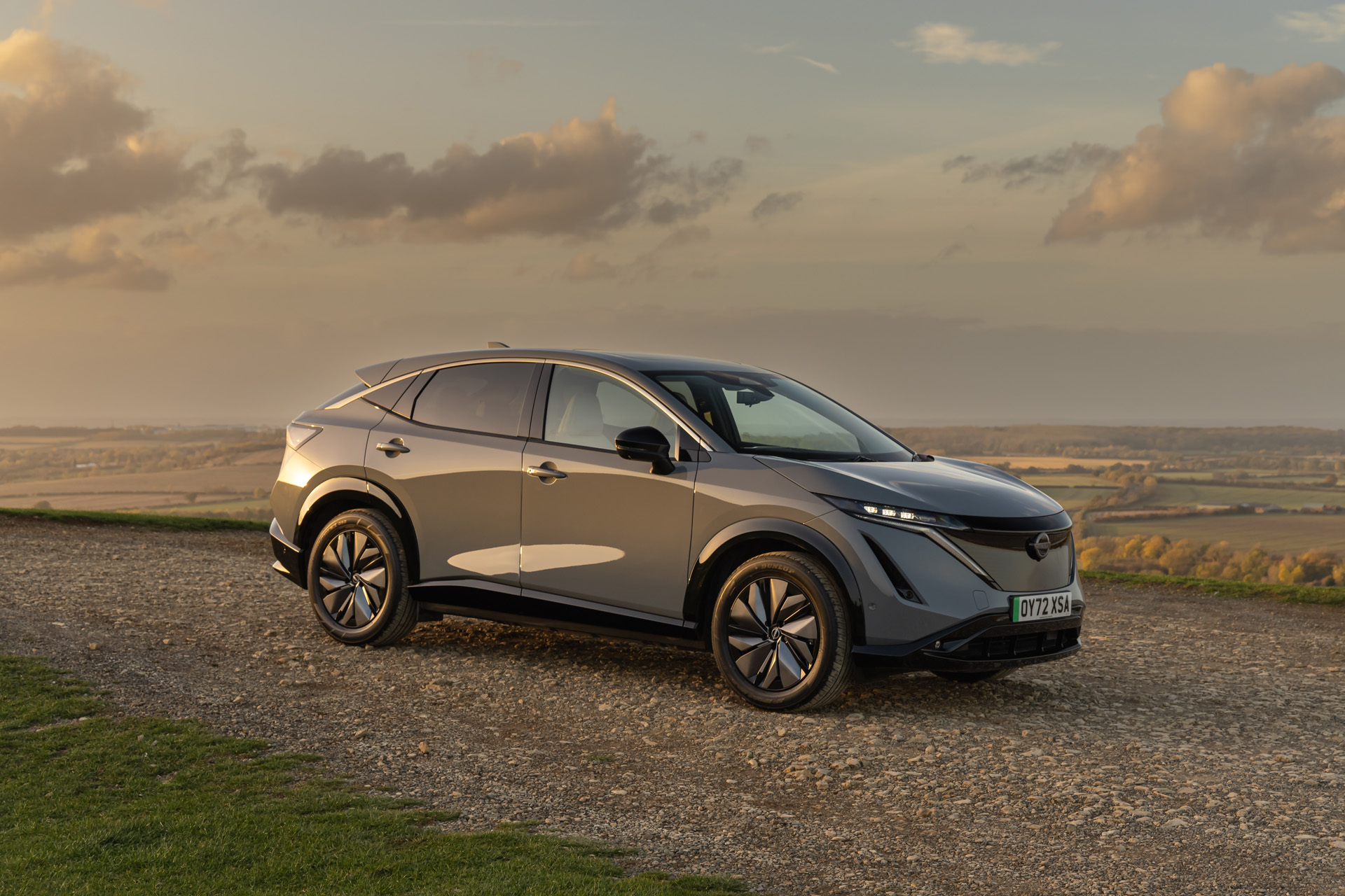 the new Nissan ARIYA grey car on a stone road with a countryside background