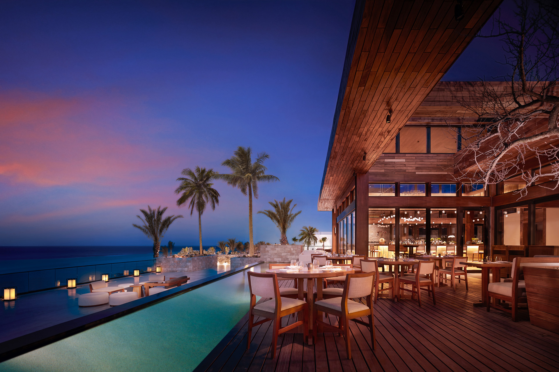 a restaurant terrace with pool overlooking the sea at dusk