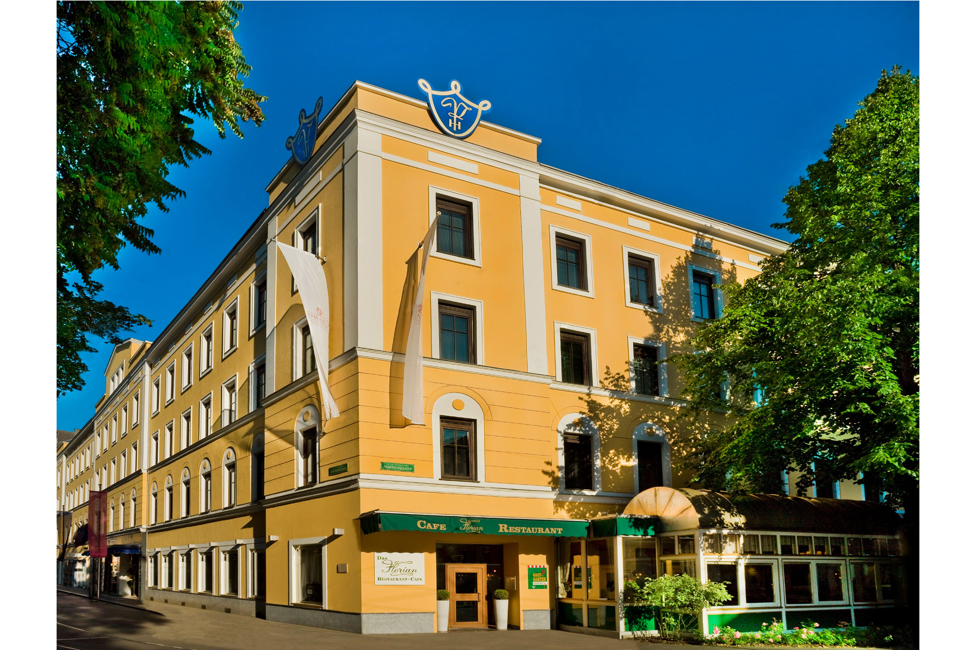 a yellow hotel in graz against a blue sky