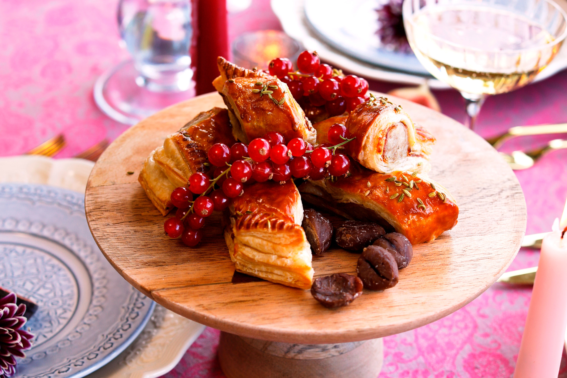 Pigs in Blankets Sausage Rolls on wooden stand on pink table